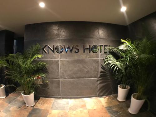 un hall avec un panneau indiquant un hôtel connu avec des plantes dans l'établissement KNOWS HOTEL, à Numazu