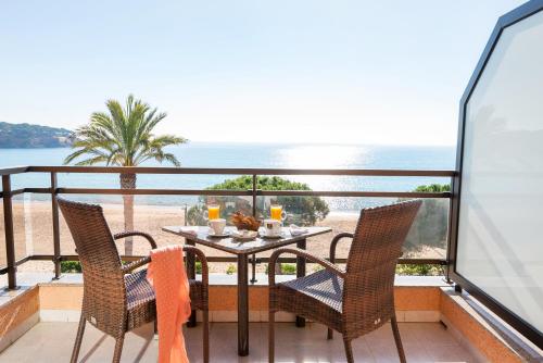 einen Tisch und Stühle auf einem Balkon mit Blick auf den Strand in der Unterkunft Hotel Restaurant Sant Pol in Sant Feliu de Guixols