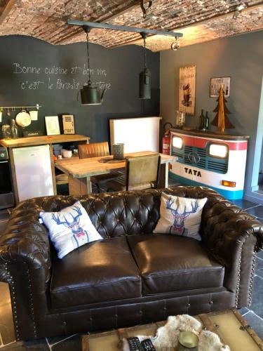 a brown leather couch in a living room with a table at Gîte de Corbion Loft1 in Ciney