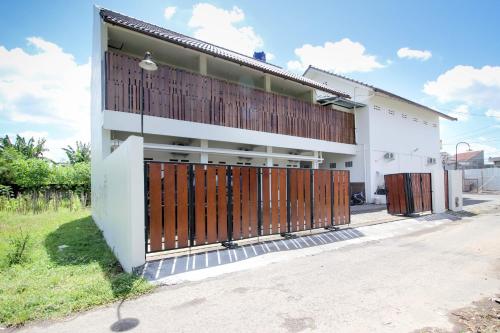 une maison blanche avec des portes brunes et une cour dans l'établissement Griya Izzara Guest House Syariah, à Sleman