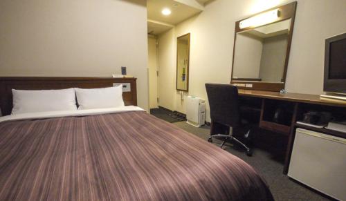 a hotel room with a bed and a desk and a mirror at Hotel Route-Inn Ichinoseki Inter in Ichinoseki