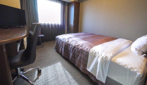 a hotel room with a bed and a desk and a desk at Hotel Route-Inn Ichinoseki Inter in Ichinoseki