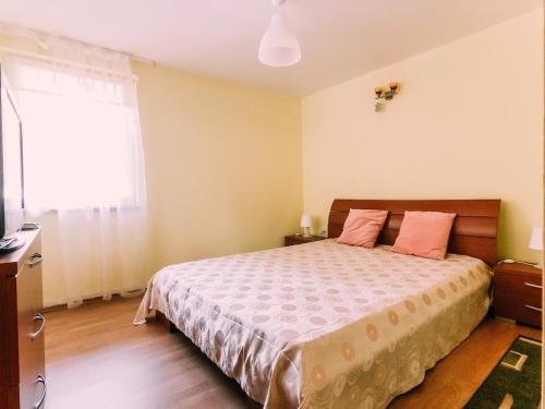 a bedroom with a bed with pink pillows and a window at Spacious Apartment near Peles in Sinaia