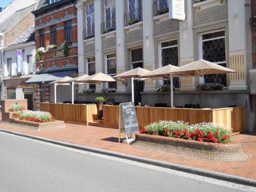 ein Restaurant mit Sonnenschirmen und Blumen vor einem Gebäude in der Unterkunft Hotel Palace in Poperinge