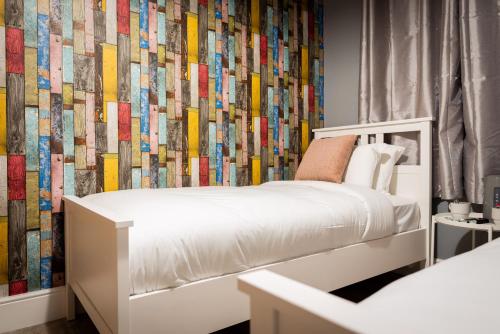 una camera con un letto bianco e una parete colorata di REM Hotel a Manchester