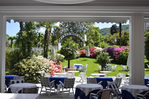 una zona pranzo all'aperto con tavoli, sedie e fiori di Hotel Royal a Stresa