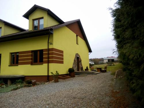 a yellow house with a gravel driveway at Pokoje na Wiejskiej in Nałęczów