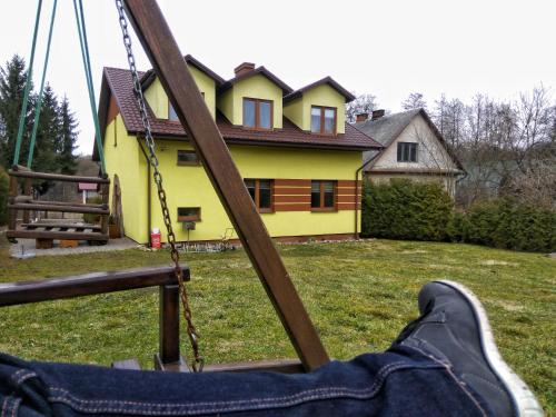 a persons feet on a swing in front of a house at Pokoje na Wiejskiej in Nałęczów