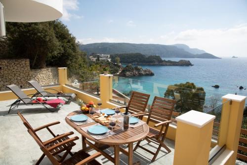 een patio met een tafel en stoelen en de oceaan bij Barbara's House in Paleokastritsa