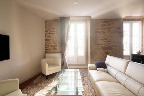 ein Wohnzimmer mit einem weißen Sofa und einem Glastisch in der Unterkunft Luxury apartment-free parking in Santiago de Compostela