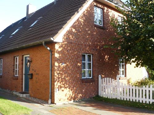 een rood bakstenen huis met een wit hek bij Ferienwohnung Seidler in Rendsburg