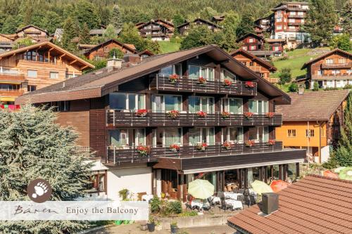 - un grand bâtiment avec balcon et fleurs dans l'établissement Alpenkräuter Hotel Bären, à Wengen