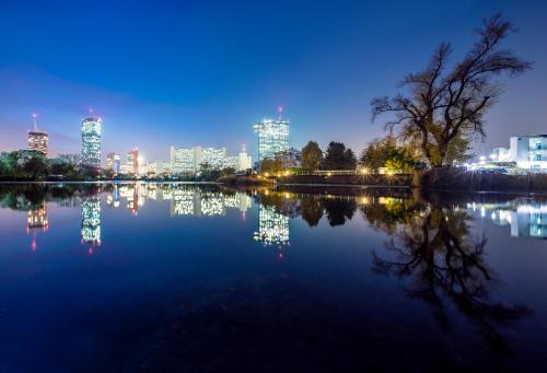 Blick auf die Skyline der Stadt von einem See in der Nacht in der Unterkunft Strandhotel Alte Donau in Wien