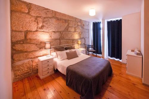 um quarto com uma parede de pedra e uma cama grande em OportoHouse no Porto