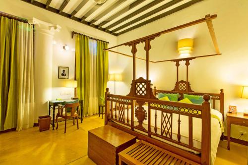 um quarto com uma cama de dossel, uma secretária e uma mesa em Maison Perumal Pondicherry - a CGH Earth Experience em Pondicherry