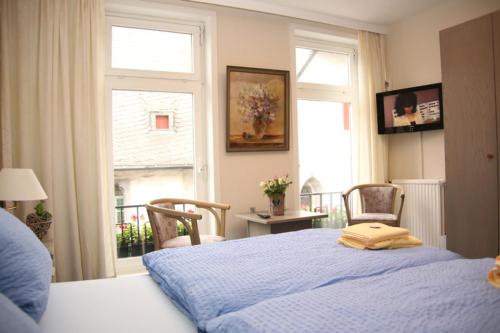 a bedroom with a blue bed with two chairs and a window at Hotel Garni Kaiserpfalz in Goslar