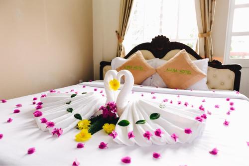 um cisne branco deitado numa cama com flores em Mui Ne Alena Hotel em Phan Thiet