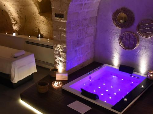 einen Whirlpool in einem Zimmer mit lila Beleuchtung in der Unterkunft Le Fornaci Imperial Lodge & Spa in Gravina in Puglia