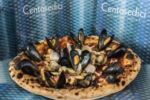 Une pizza avec des moules assises sur une table dans l'établissement Hotel Ristorante Centosedici, à Terracine