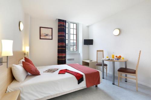 a bedroom with a bed and a table with a chair at Vacancéole - Les Demeures Champenoises in Épernay