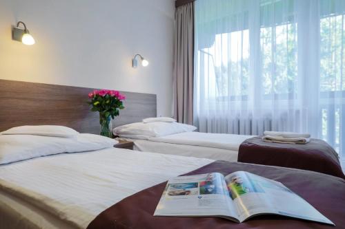 una habitación de hotel con 2 camas y un libro sobre ellas en Hotel***NAT Piwniczna Zdrój, en Piwniczna-Zdrój