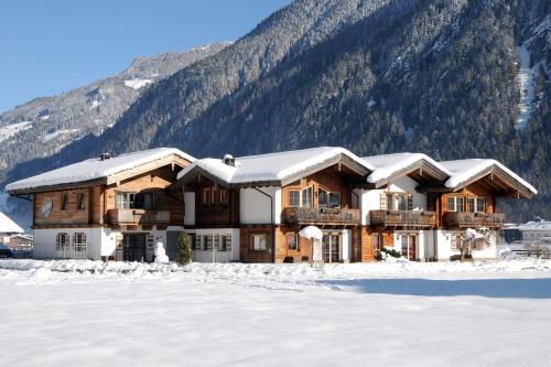 una cabaña de madera en la nieve con una montaña en Chalet Schnee, en Mayrhofen