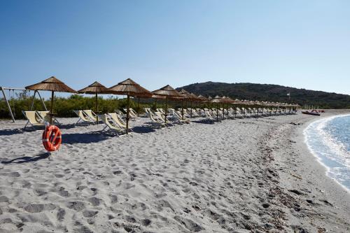 een zandstrand met stoelen en parasols en de oceaan bij Residence Baia Salinedda in San Teodoro