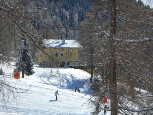 Skihütte Zams في زامز: شخصين يتزحلق على منحدر مغطى بالثلج أمام المبنى