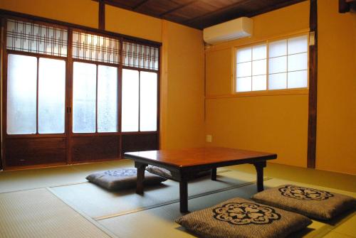 Zimmer mit einem Tisch und 2 großen Fenstern in der Unterkunft NARAigoto EENA HOUSE in Nara