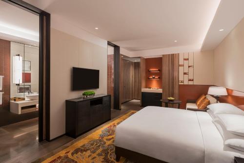 ein Hotelzimmer mit einem Bett und einem TV in der Unterkunft Grand Hyatt Changsha in Changsha