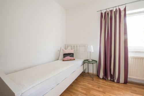 ein weißes Bett in einem Zimmer mit Fenster in der Unterkunft Pension Rosenhof in Linz