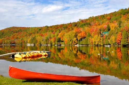 a red boat on a lake with fall foliage at Le Boisé du Lac in Mont-Tremblant