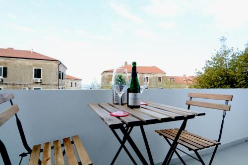 einen Tisch mit 2 Stühlen und eine Flasche Wein auf dem Balkon in der Unterkunft La Piazza in Umag