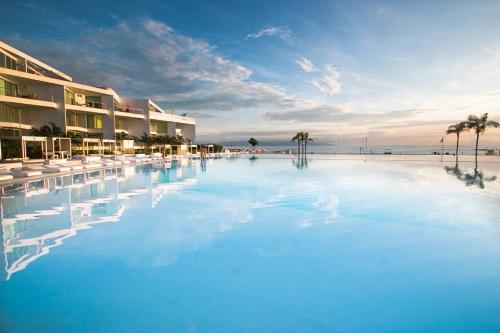 a large swimming pool next to a beach with palm trees at AMAZING BEACH FRONT - ACQUA NUEVO VALLARTA - MX in Nuevo Vallarta 