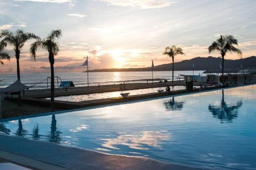 a swimming pool next to a beach with palm trees at AMAZING BEACH FRONT - ACQUA NUEVO VALLARTA - MX in Nuevo Vallarta 