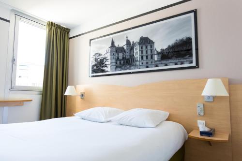 una habitación de hotel con una cama y una foto en la pared en Hotel inn Grenoble Eybens Parc des Expositions Ex Kyriad, en Eybens