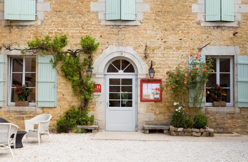 um edifício de tijolos com uma porta branca e janelas em Hotel-restaurant Les Caudalies em Arbois