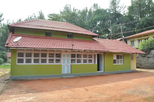 a small green house with a red roof at Thanmaya Homestay in Chikmagalūr