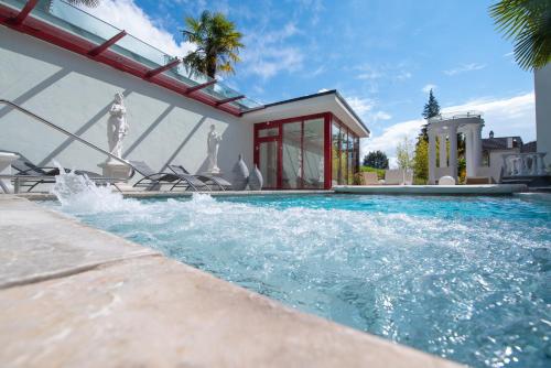 uma piscina com cadeiras e uma casa em Hotel Rössli Gourmet & Spa em Weggis