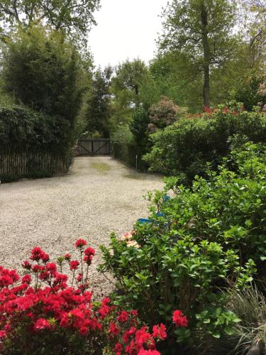 einen Garten mit roten Blumen und einem Zaun in der Unterkunft Chambre d'HÔTE Maison De L'amitié in Lanton