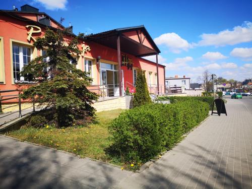 une maison rouge avec un arbre devant elle dans l'établissement Hotel Gryf, à Kościerzyna