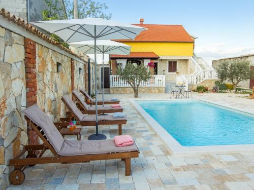 - une piscine avec 2 chaises longues et un parasol dans l'établissement Holiday home Iva with pool, à Sukošan