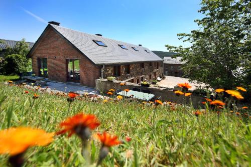 uma casa com um campo de flores em frente em Ferme Hurlet em Stavelot