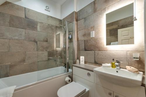 a bathroom with a sink and a toilet and a tub at Bryn Derwen with Private Car Park in Llandudno