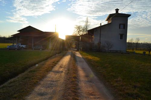 una strada sterrata di fronte a un fienile con il tramonto di Agriturismo La Farazzina a Oleggio