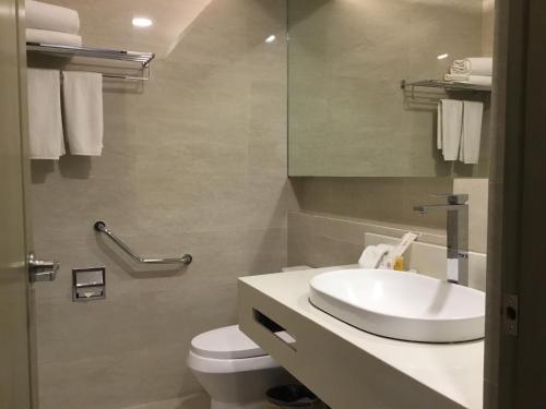 uma casa de banho com um lavatório, um WC e um espelho. em L'Fisher Hotel Bacolod em Bacolod