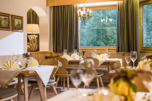 restauracja ze stołami, krzesłami i oknami w obiekcie Hotel Haflingerhof w mieście Oberau