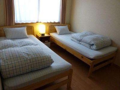 2 camas en una habitación pequeña con ventana en Guesthouse Mintaro Hut, en Yamagata