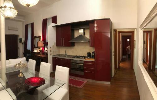 a kitchen with red cabinets and a glass table with white chairs at Colosseo Room in Rome