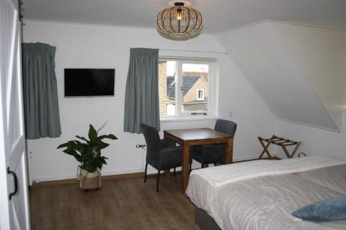 Schlafzimmer mit einem Bett, einem Schreibtisch und einem Fenster in der Unterkunft Hiltop in Domburg